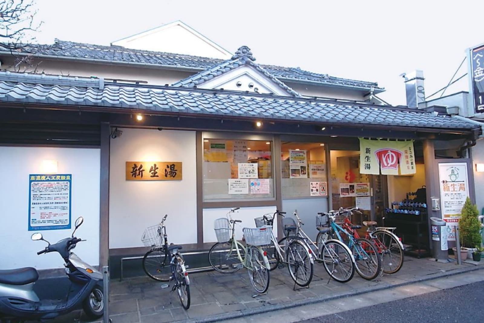 新生湯の外観。瓦屋根の玄関と暖簾
